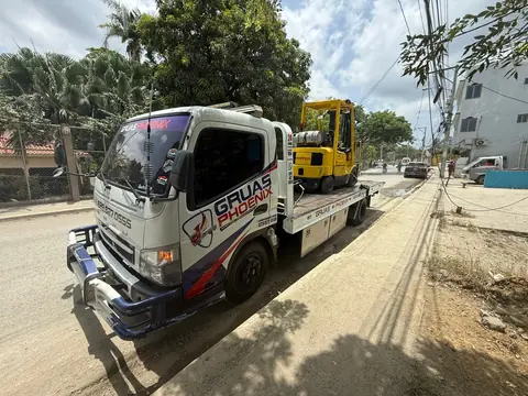 Camión plataforma de Grúas Phoenix transportando un montacargas amarillo