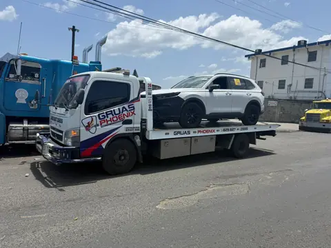 Grúa de Grúas Phoenix trasladando una SUV blanca sobre plataforma